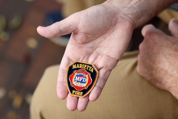 Former Marietta Firefighter Webb Smith holds the medal he received for being the 2020 Firefighter Engineer of the Year, shown at the Marietta Square, Thursday, November 3, 2022, in Marietta, Ga. Smith resigned after 15 years of service. (Jason Getz / Jason.Getz@ajc.com)