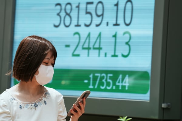 A person walks in front of an electronic stock board showing Japan's Nikkei index at a securities firm Monday, June 23, 2025, in Tokyo. (AP Photo/Eugene Hoshiko)