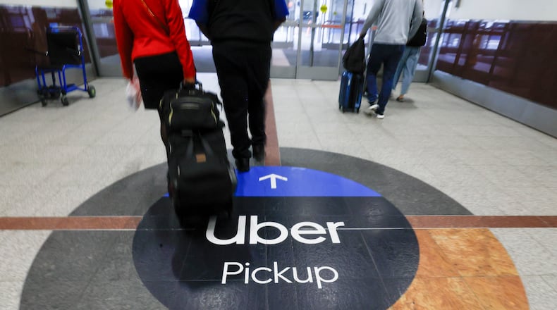 Travelers exit the airport toward the designated area in the North Terminal at Hartsfield-Jackson Atlanta International Airport on Thursday, April 24, 2025. At the moment, it’s not clear where Uber and Lyft premium “Black” drivers are legally allowed to pick up passengers. 
(Miguel Martinez/ AJC)