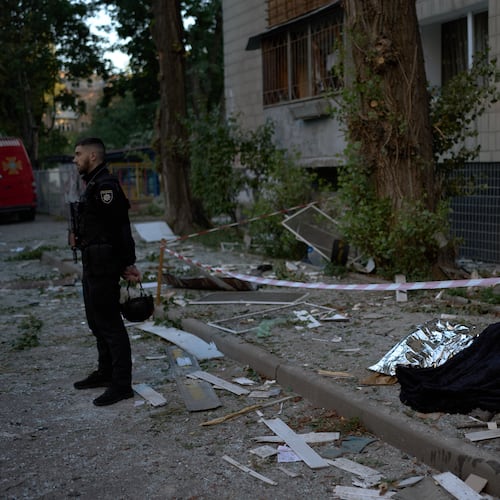 A policeman stands next to the bodies of two people killed during an overnight Russian attack in Kyiv, Ukraine, Thursday, Aug. 20, 2026. (AP Photo/Francisco Seco)