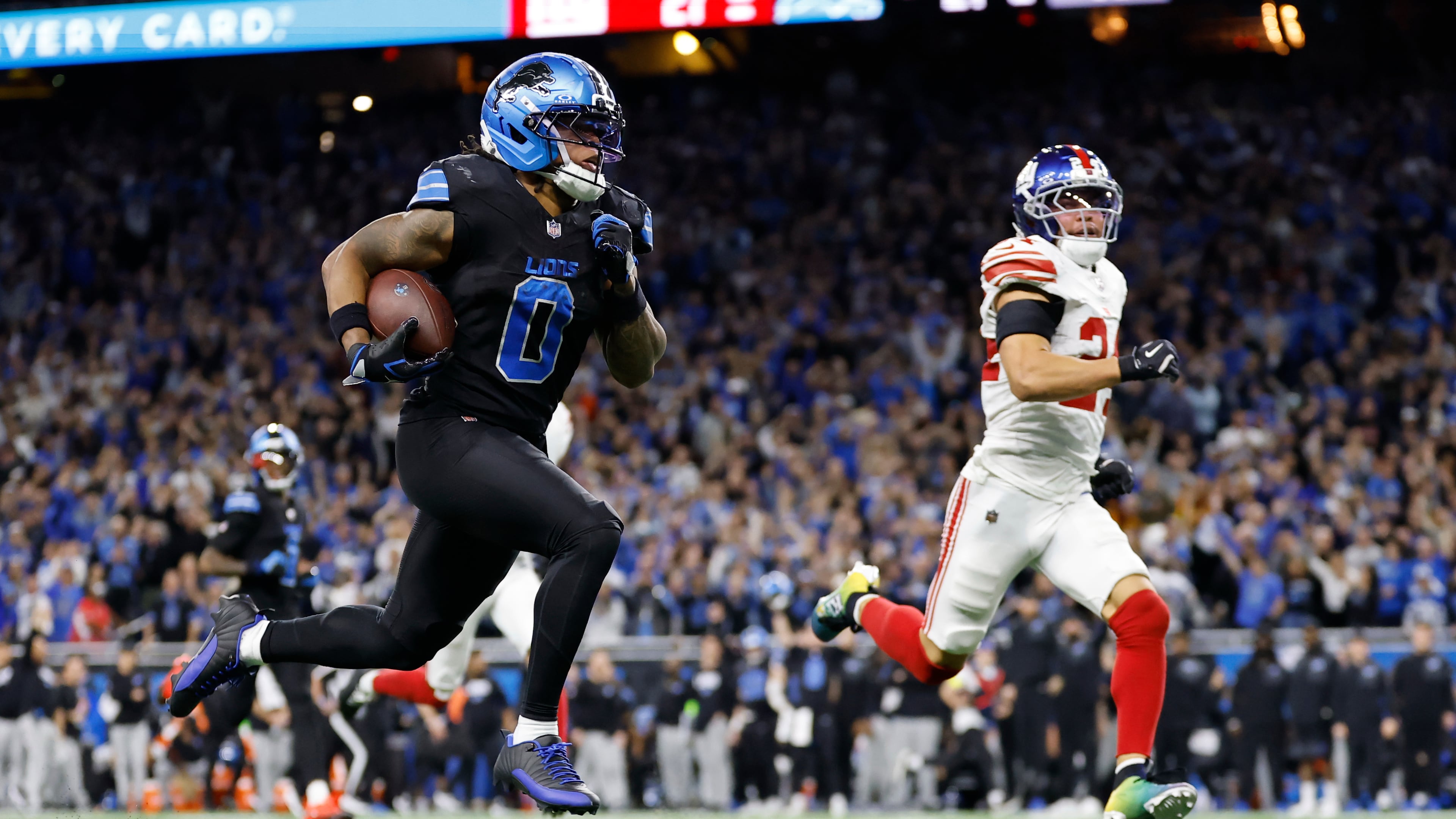 Detroit Lions running back Jahmyr Gibbs (0) runs past New York Giants safety Dane Belton (24) for a touchdown in overtime of an NFL football game in Detroit, Sunday, Nov. 23, 2025. (AP Photo/Rey Del Rio)
