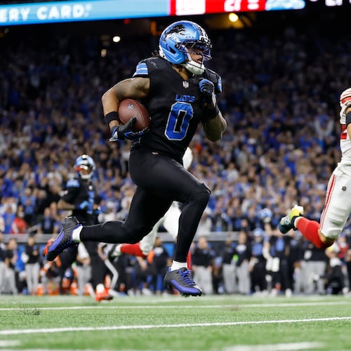 Detroit Lions running back Jahmyr Gibbs (0) runs past New York Giants safety Dane Belton (24) for a touchdown in overtime of an NFL football game in Detroit, Sunday, Nov. 23, 2025. (AP Photo/Rey Del Rio)