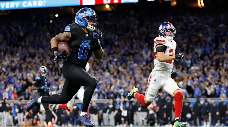 Detroit Lions running back Jahmyr Gibbs (0) runs past New York Giants safety Dane Belton (24) for a touchdown in overtime of an NFL football game in Detroit, Sunday, Nov. 23, 2025. (AP Photo/Rey Del Rio)
