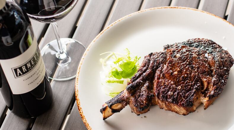 Although Arnette’s Chop Shop in Brookhaven is closed for dine-in service, customers still can enjoy its steakhouse fare, like a 22-ounce cowboy rib-eye (pictured), paired with the house label red wine. CONTRIBUTED BY HENRI HOLLIS