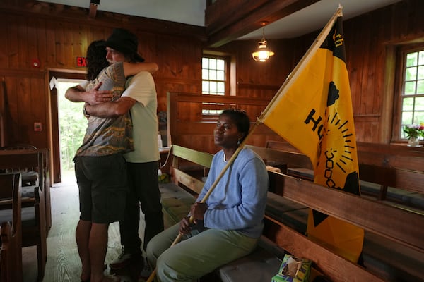Casey Oware, a member of the Princeton Friends Meeting, seated, holds a flag while Stuart Sydenstricker, right, and Jules Wing Vasquez hug after completing a portion of the Quaker March to Washington at the Quaker Meeting House in Princeton, N.J. (AP Photo/Luis Andres Henao)