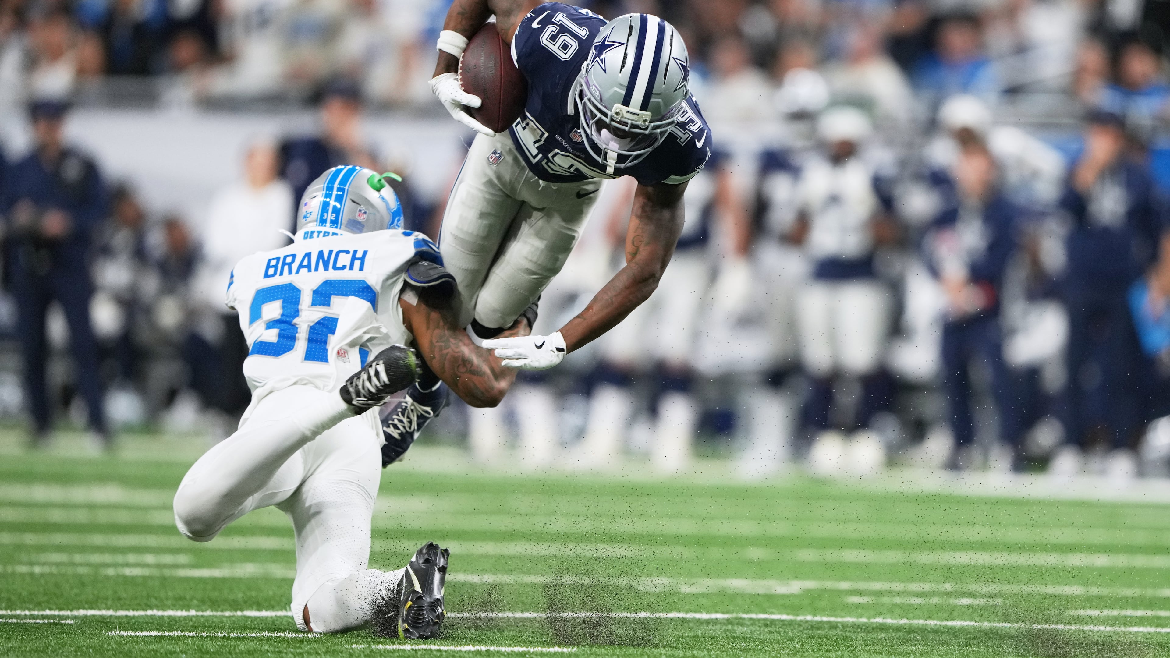 Dallas Cowboys wide receiver Ryan Flournoy (19) takes a hit from Detroit Lions safety Brian Branch (32) during the second half of an NFL football game Thursday, Dec. 4, 2025, in Detroit. (AP Photo/Ryan Sun)