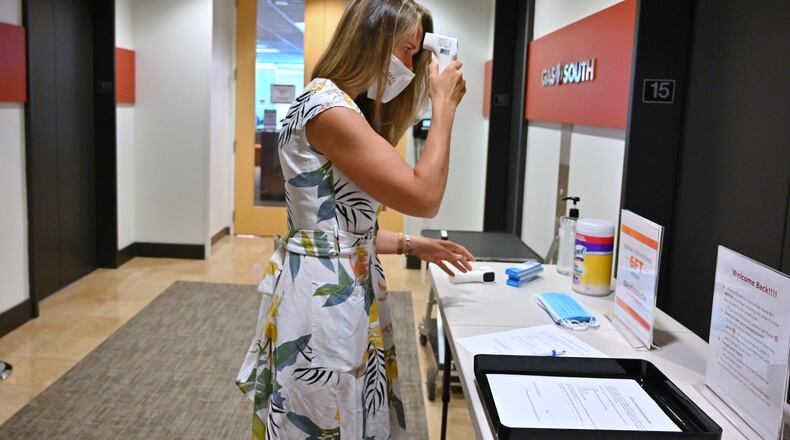 Carley Stephens, a community affairs manager at Gas South, checks her temperature before she walks into the company’s offices in Cobb County. Shoppers are hitting stores and filling parking lots. Some diners are returning to sit-down restaurants. But many of metro Atlanta’s white-collar towers and office parks are still lonely places as people work remotely during the coronavirus pandemic. (Hyosub Shin / Hyosub.Shin@ajc.com)