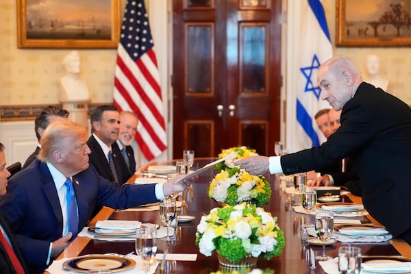 Israel's Prime Minister Benjamin Netanyahu, right, hands President Donald Trump a folder during a meeting in the Blue Room of the White House, Monday, July 7, 2025, in Washington. (AP Photo/Alex Brandon)