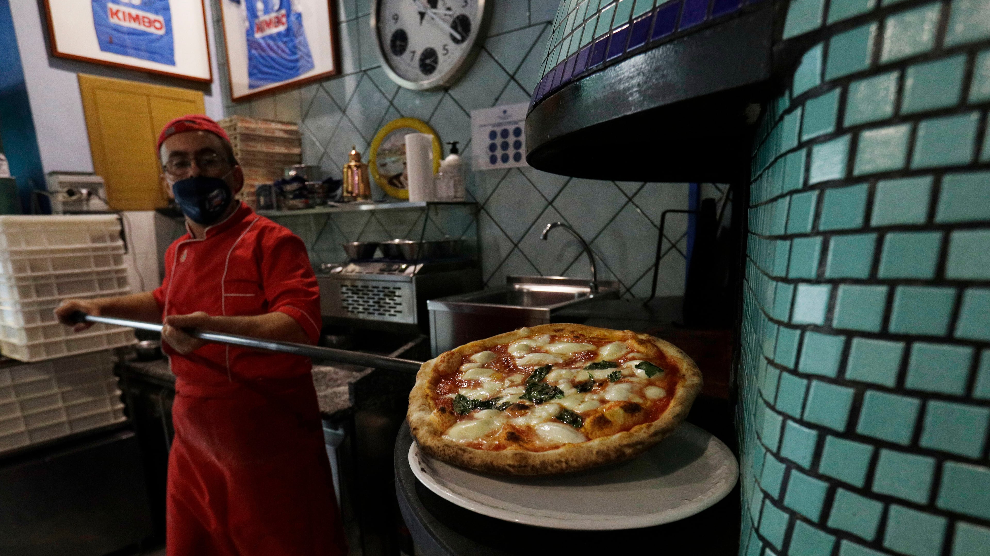 FILE -Eugenio Iorio bakes a pizza at a restaurant in Naples, Italy, Saturday, Nov. 14, 2020. (AP Photo/Gregorio Borgia, File)