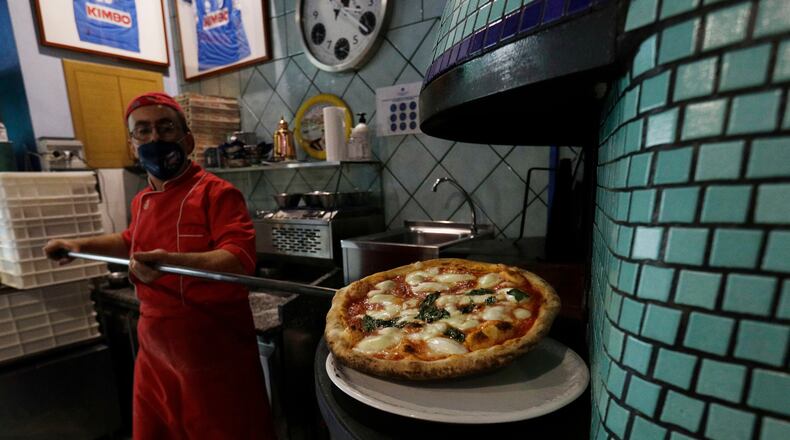 FILE -Eugenio Iorio bakes a pizza at a restaurant in Naples, Italy, Saturday, Nov. 14, 2020. (AP Photo/Gregorio Borgia, File)