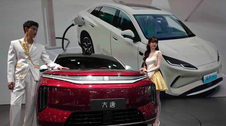 FILE - Models stand next to a latest EV car from Chinese automaker BYD showcased at the Auto China 2026, in Beijing, April 25, 2026. (AP Photo/Andy Wong, File)