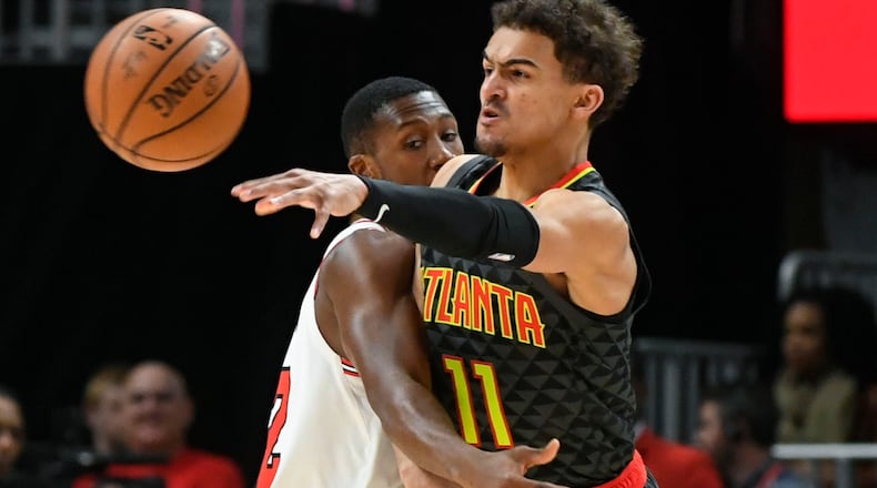 Hawks guard Trae Young (11) makes a pass as Chicago Bulls guard Kris Dunn defends during the first half of an NBA basketball game Friday, March 1, 2019, in Atlanta. (AP Photo/John Amis)
