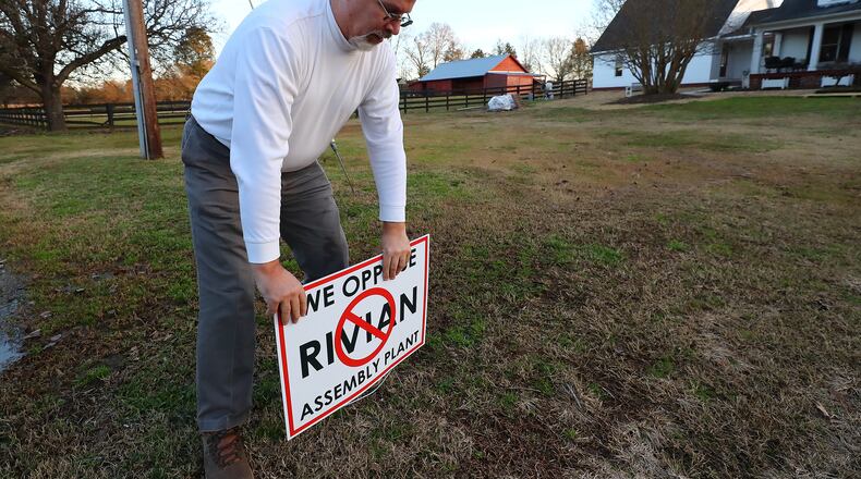 Keith Wilson, who said he moved from Cobb County to his 17-acre Rutledge farm, posting a sign in his yard opposing the Rivian assembly plant on Tuesday, Jan. 18, 2022, in Rutledge. "Curtis Compton / Curtis.Compton@ajc.com”`