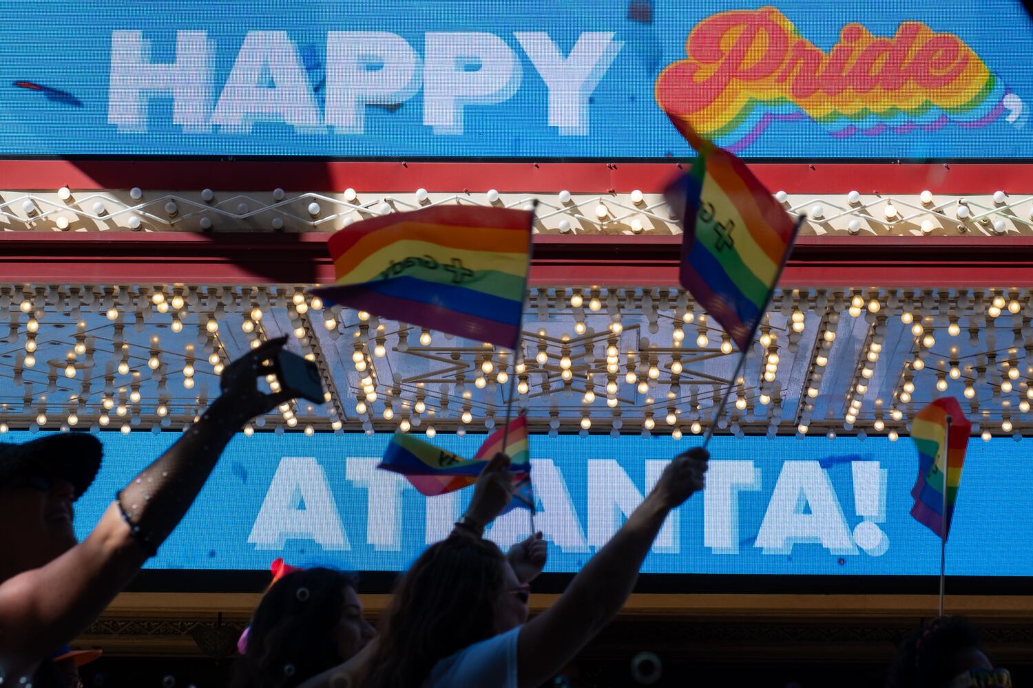 Atlanta Pride Parade participants wave flags and pass the Fox Theatre marquee on Sunday, Oct. 12, 2025. (Ben Gray for the AJC)