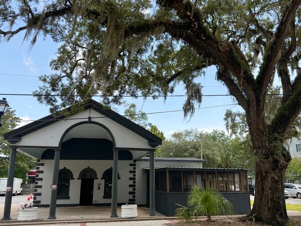 The exterior of a building with a large car port with an old live oak tree craning over it.