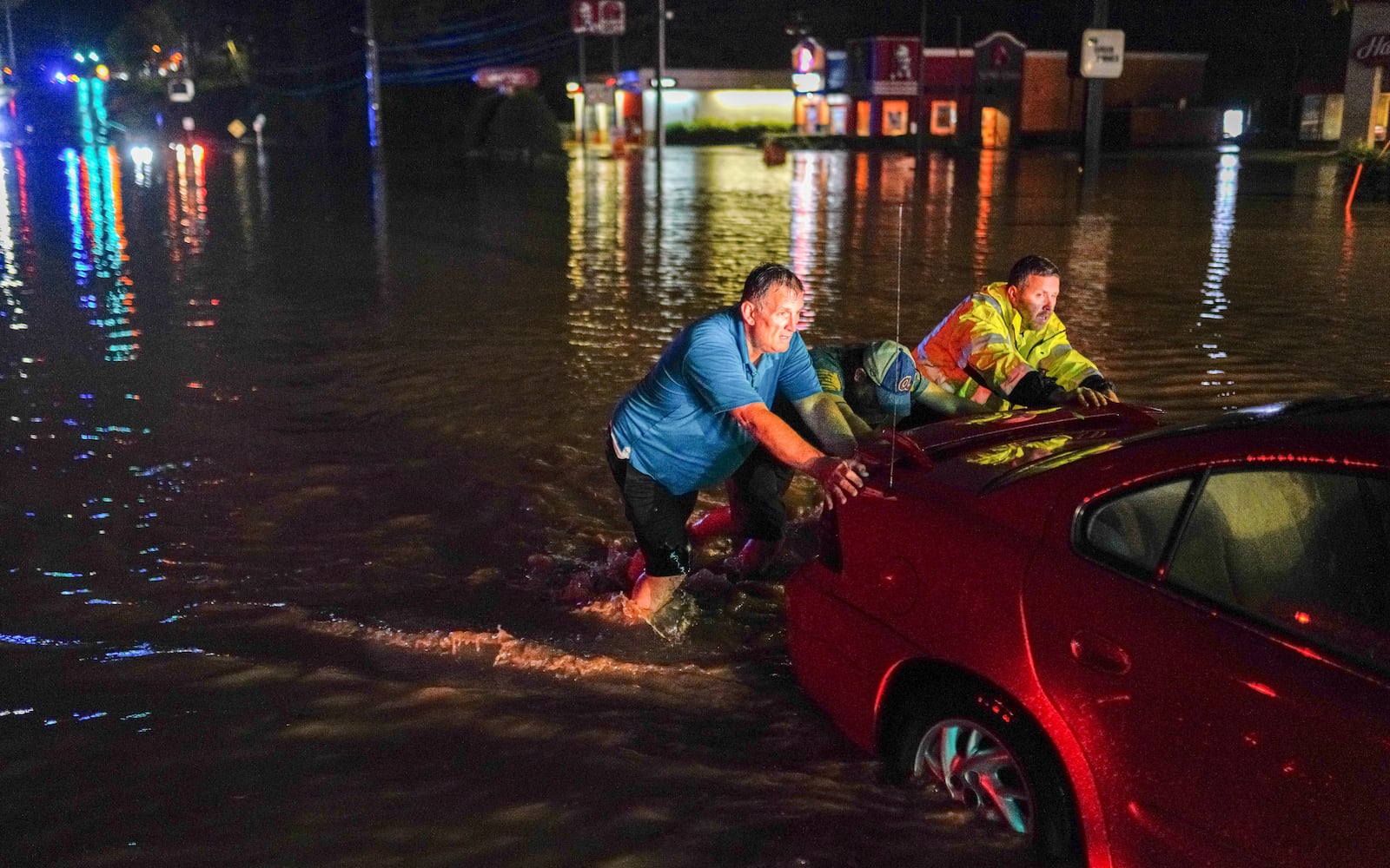 Bystander assistant  tow truck driver in pushing a sedan from flood waters on Delk road. The vehicle stalled in floodwaters that engulfed Delk road. Ben Hendren for the AJC