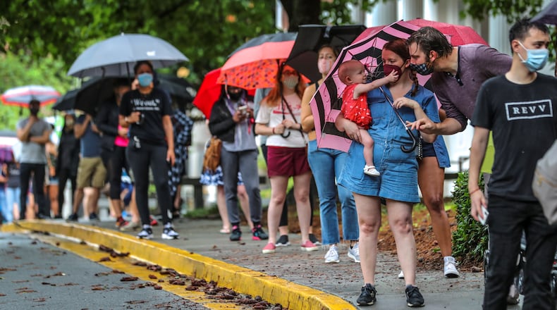June 5, 2020 Atlanta: Amanda McElveen holds 1-year old Luna (left) as Dad, Justin McElveen (right) interacts while they and other voters lined up in the rain on Friday, June 6, 2020 at Garden Hills Elementary School located at 285 Sheridan Dr NE, in Atlanta where the wait for early voting was between 1-2 hours. Georgia voters headed to the polls Friday for a busy last day of early voting before Tuesday’s primary election day. Voters have faced lines at some locations as election officials space them 6 feet apart and limit the number of people allowed inside at a time. Poll workers are also taking time to wipe down touchscreens. Over 1.1 million voters have already cast their ballots in the primary, including 262,000 in-person voters so far. Another 847,000 people have returned absentee ballots, a record number of remote voters during the coronavirus pandemic. While in-person early voting ends today, absentee ballots can still be counted if they’re received by the time polls close Tuesday. About 753,000 voters who requested absentee ballots hadn’t returned them through Thursday. Absentee ballots can be deposited in drop boxes any time before 7 p.m. Tuesday. Absentee ballots returned by mail will only be counted if they’re received by election offices by Tuesday. JOHN SPINK/JSPINK@AJC.COM