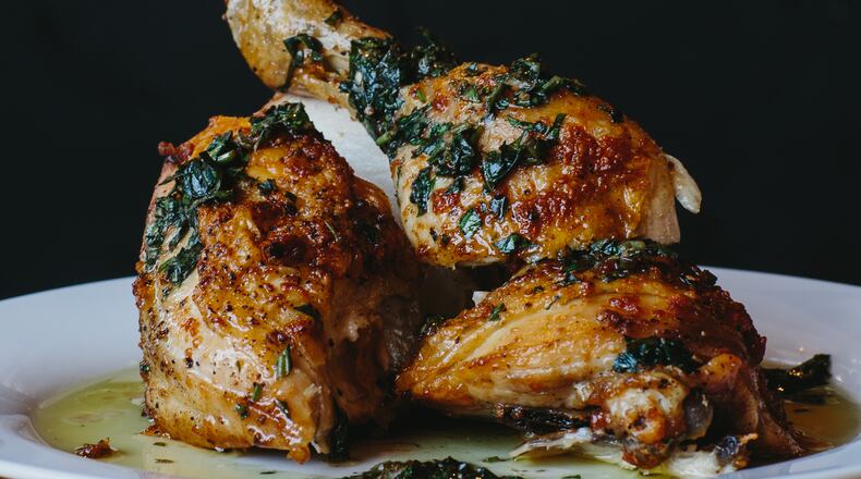 Simple roast chicken is served in a pool of olive oil and herbs at Brezza Cucina. Credit: Andrew Thomas Lee