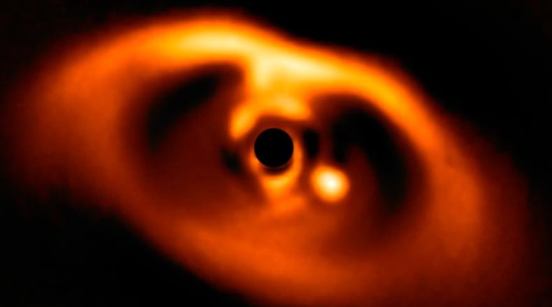 The photo provided by the European Southern Observatory ESO taken from the SPHERE instrument on ESO's Very Large Telescope is the first clear image of a planet caught in the very act of formation around the dwarf star PDS 70. The planet stands clearly out, visible as a bright point to the right of the centre of the image, which is blacked out by the coronagraph mask used to block the blinding light of the central star. (ESO via AP)