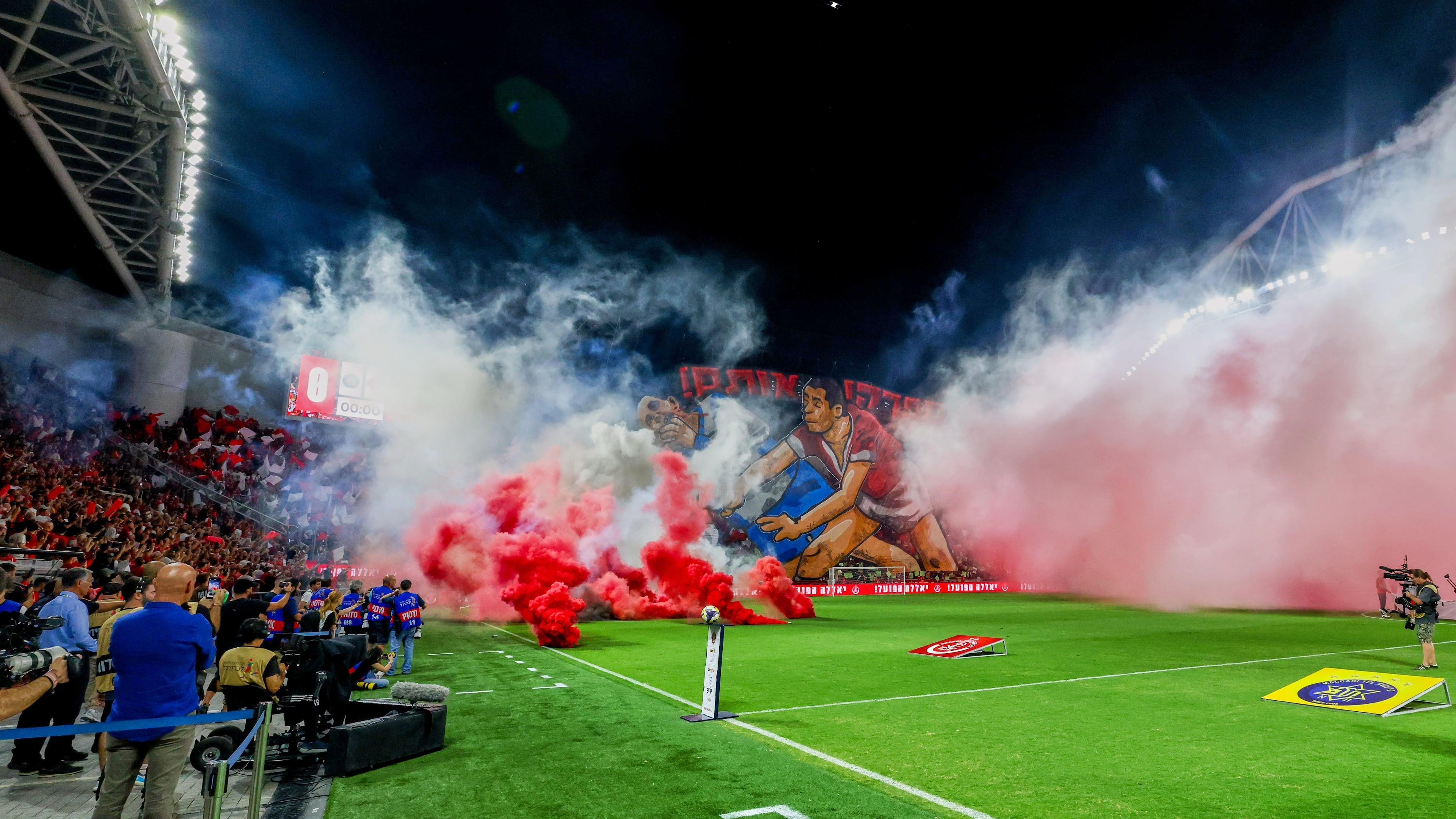 Smoke from flares thrown by fans fills the field before the soccer derby between Maccabi Tel Aviv and Hapoel Tel Aviv was called off Sunday after pregame disturbances led police to deem it unsafe to proceed at Bloomfield Stadium in Tel Aviv, Israel, Sunday, Oct. 19, 2025 . (AP Photo/Nir Keidar)