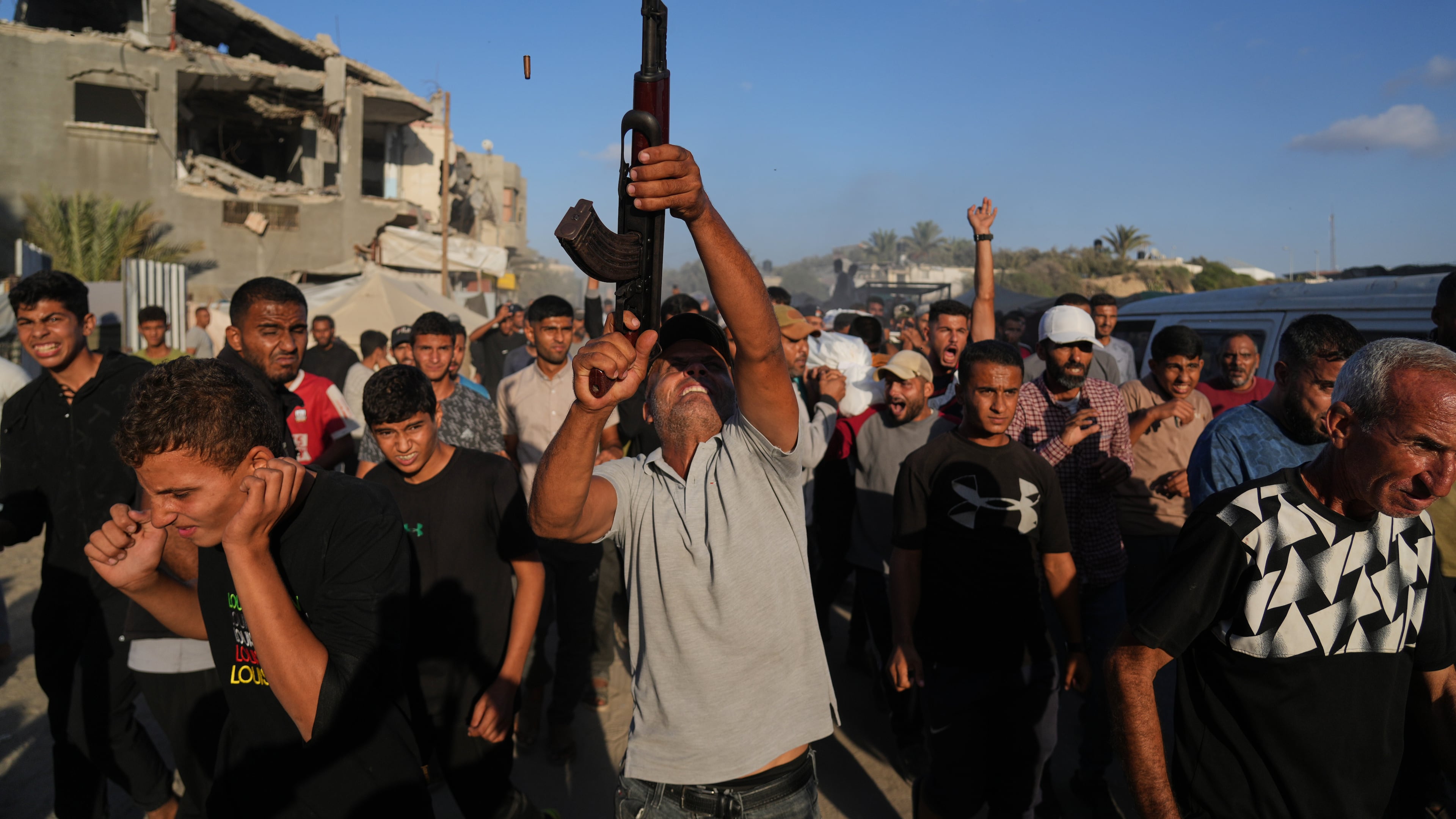 An armed man shoots in the air during the funeral of Palestinians killed by Israeli fire, in Deir al-Balah, Gaza Strip, Sunday, Oct. 19, 2025. (AP Photo/Abdel Kareem Hana)