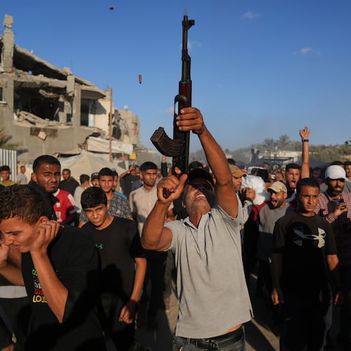 An armed man shoots in the air during the funeral of Palestinians killed by Israeli fire, in Deir al-Balah, Gaza Strip, Sunday, Oct. 19, 2025. (AP Photo/Abdel Kareem Hana)