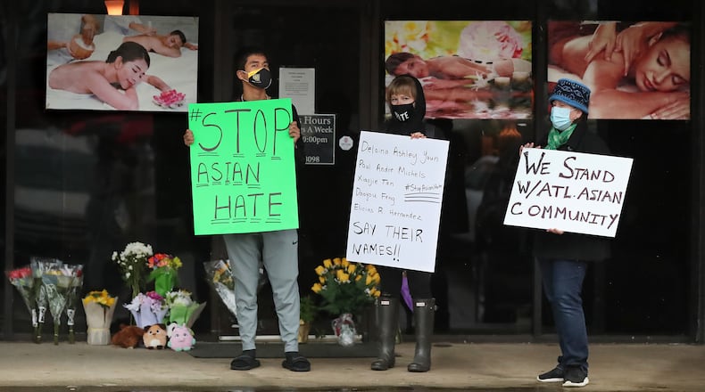 Jesus Estrella (from left), Shelby S., and Shannon Deisen show support for the Asian community standing outside Youngs Asian Massage in Acworth, where four people were killed Wednesday.