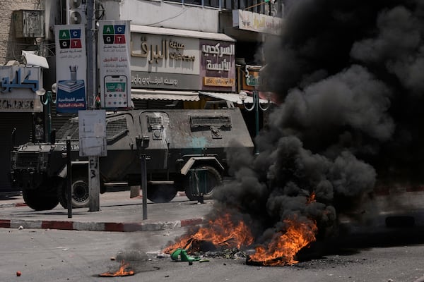 An Israeli armoured vehicle drives near burning tires during a military raid in the West Bank city of Nablus, Tuesday, June 10, 2025. (AP Photo/Majdi Mohammed)