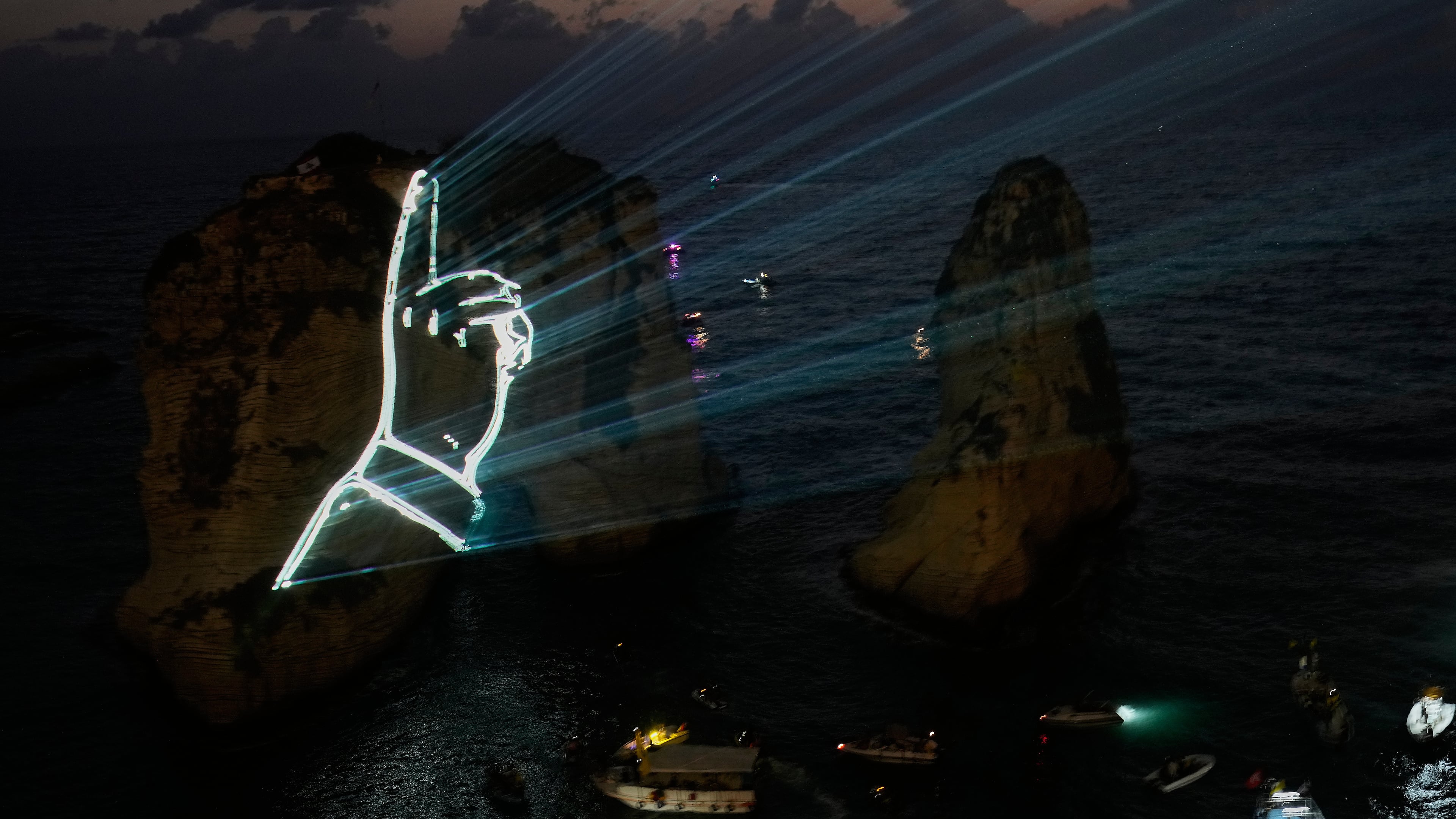 The landmark Raouche sea rock is illuminated by the hand of the late Hezbollah leader Sayyed Hassan Nasrallah during an event commemorating his death in Israeli airstrikes nearly a year ago, in Beirut, Lebanon, Thursday, Sept. 25, 2025. (AP Photo/Hussein Malla)