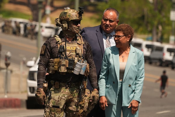 Los Angeles Mayor Karen Bass walks with a federal agent at MacArthur Park Monday, July 7, 2025, in Los Angeles. (AP Photo/Damian Dovarganes)