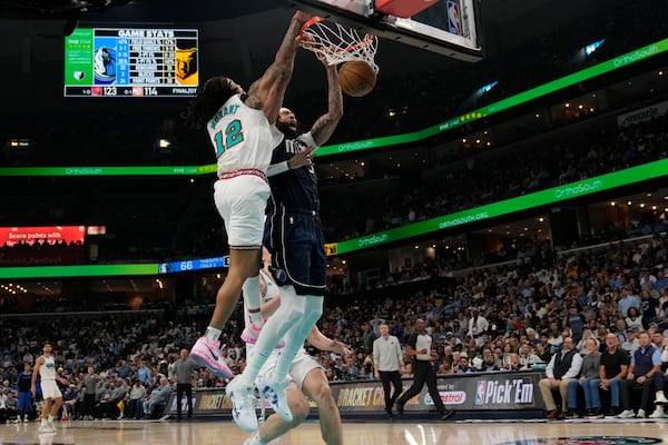 Dallas Mavericks forward Anthony Davis, right, dunks the ball past Memphis Grizzlies guard Ja Morant (12) during the second half of an NBA play-in tournament basketball game Friday, April 18, 2025, in Memphis, Tenn. (AP Photo/George Walker IV)