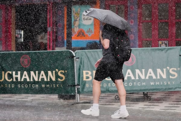 A pedestrian makes his way along a street during a rain shower Tuesday, July 15, 2025, in Orlando, Fla. (AP Photo/John Raoux)
