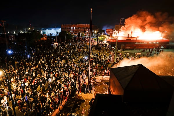 FILE - Protestors demonstrate outside of the burning Minneapolis 3rd Police Precinct in Minneapolis on May 28, 2020. (AP Photo/John Minchillo, File)