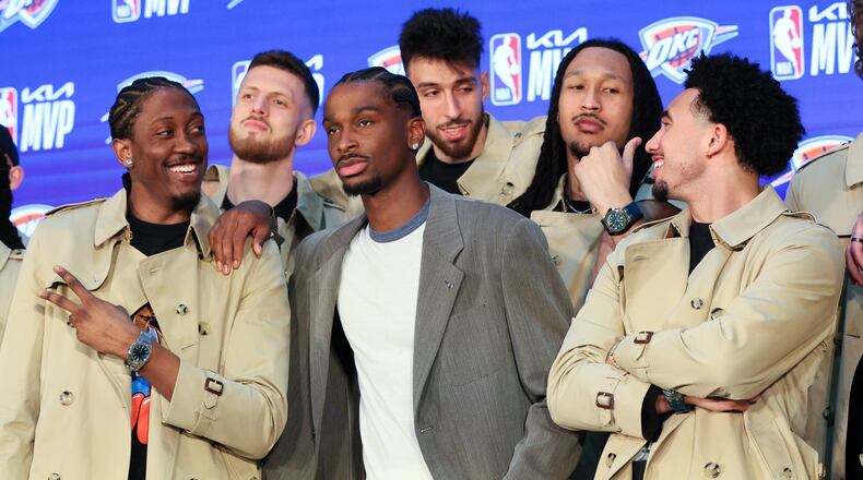 Oklahoma City Thunder guard Shai Gilgeous-Alexander, center, poses with teammates Jalen Williams, left, Isaiah Hartenstein, second from left, Chet Holmgren, center back, Jaylin Williams, second from right, and Jared McCain, right, in Burberry trench coats bought by Gilgeous-Alexander during a news conference after he was named the NBA basketball MVP, Sunday, May 17, 2026, in Oklahoma City. (AP Photo/Nate Billings)