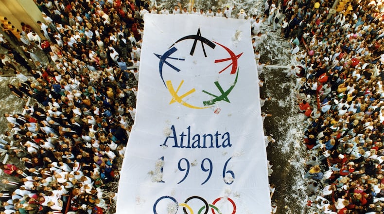 An Atlanta 1996 banner makes its way north along Peachtree Street Monday during an Olympic Parade celebrating Atlanta's winning bid for the 1996 Games. Joey Ivansco/AJC File