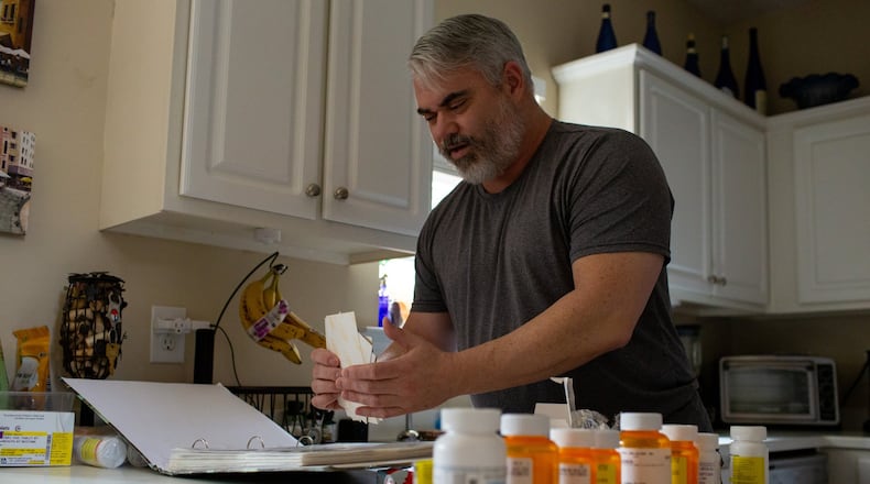 Bruce Barber sifts through photos from his deployment during the Gulf War in his home in Kennesaw. Barber has had problems getting medical appointments despite the MISSION Act, a new law that is supposed to help veterans get better, faster care outside of the VA system. It took Barber, a retired veteran from the Gulf War, 52 days to get a consultation on his war-injured neck because of fumbles and delays. (Photo/Rebecca Wright for the AJC)