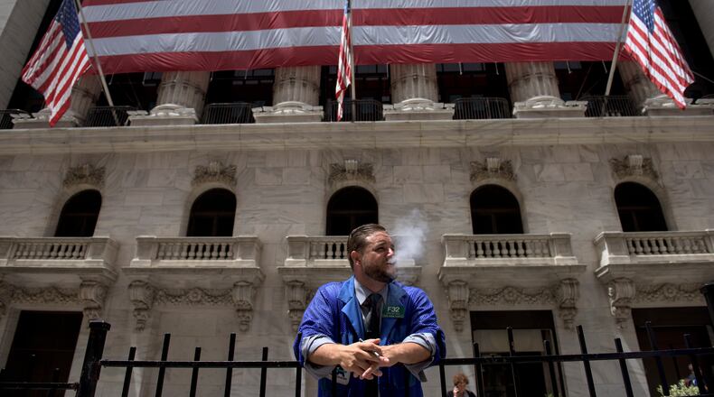A trader smokes outside the New York Stock Exchange, where all trading of listed stocks was unexpectedly halted late on the morning of July 8, 2015. Exchange officials were quick to say that technical glitches rather than malicious hacking was to blame, but there is little precedent for difficulties on this scale. (Andrew Renneisen/The New York Times)