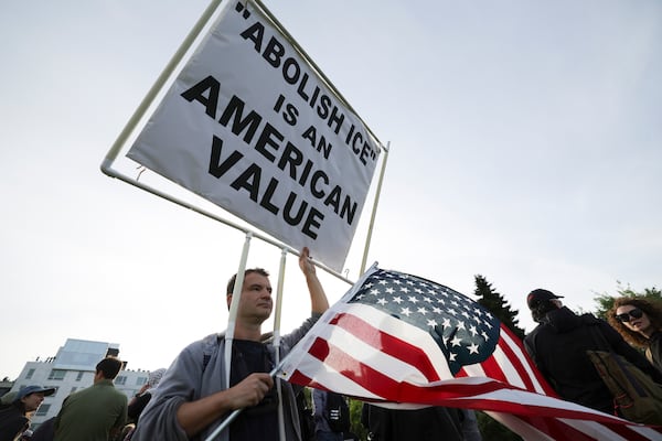 People hold up signs during a protest against federal immigration arrests, Wednesday, June 11, 2025, in Seattle. (AP Photo/Ryan Sun)