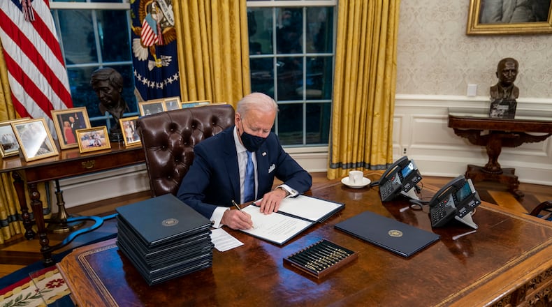 President Joe Biden signs executive orders during his first minutes in the Oval Office of the White House in Washington, on Inauguration Day, Wednesday, Jan. 20, 2021. In 17 executive orders, memorandums and proclamations signed hours after his inauguration, Biden moved swiftly on Wednesday to dismantle Trump administration policies his aides said have caused the “greatest damage” to the nation. (Doug Mills/The New York Times)