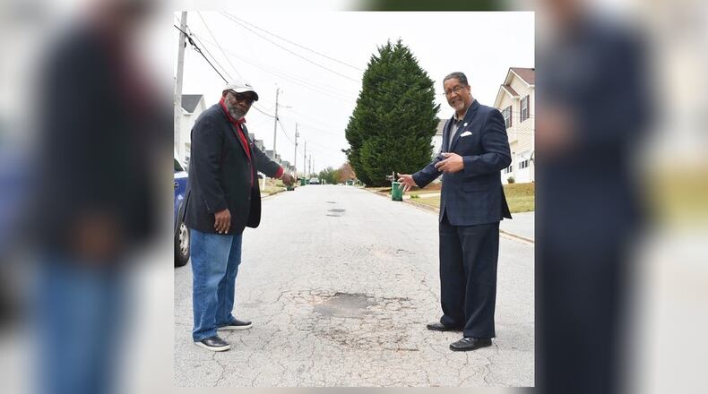 Councilman Rob Turner (left) and Mayor Jason Lary pose in front of a pothole on a Stonecrest road.