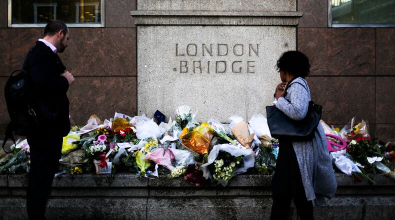 People look at the floral tributes placed at London Bridge to commemorate the victims of Saturday's attack in London, Tuesday, June 6, 2017. British police on Tuesday named the third London Bridge attacker as an Italian national of Moroccan descent, and Italian officials said they had passed on their concerns about him to British intelligence officials last year. (AP Photo/Markus Schreiber)