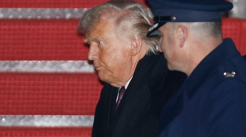 President Donald Trump, left, is greeted by Air Force Col. Christopher M. Robinson, commander of the 89th Airlift Wing, right, after walking down the stairs of Air Force One, upon his arrival at Joint Base Andrews, Md., Thursday, Jan. 22, 2026, after returning from the World Economic Forum in Davos, Switzerland.(AP Photo/Luis M. Alvarez)