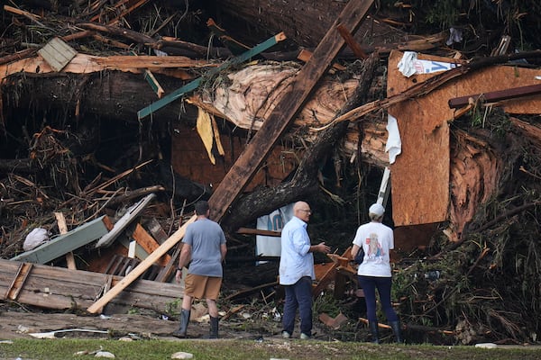People look at debris on the banks of the Guadalupe River after a flash flood swept through the area Saturday, July 5, 2025, in Hunt, Texas. (AP Photo/Julio Cortez)
