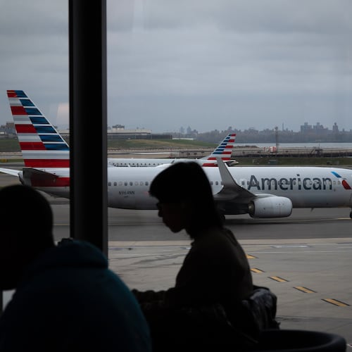 People wait for flights as an American Airlines plane taxis at LaGuardia Airport (LGA), in the Queens borough of New York, Sunday, Nov. 9, 2025. (AP Photo/Adam Gray)