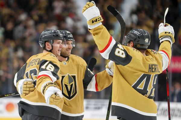 Vegas Golden Knights left wing Pavel Dorofeyev (16) celebrates with defenseman Shea Theodore (27) and center Tomas Hertl (48) after Dorofeyev's goal during the second period in Game 1 of an NHL hockey Stanley Cup first-round playoff series against the Minnesota Wild, Sunday, April 20, 2025, in Las Vegas. (AP Photo/Ian Maule)