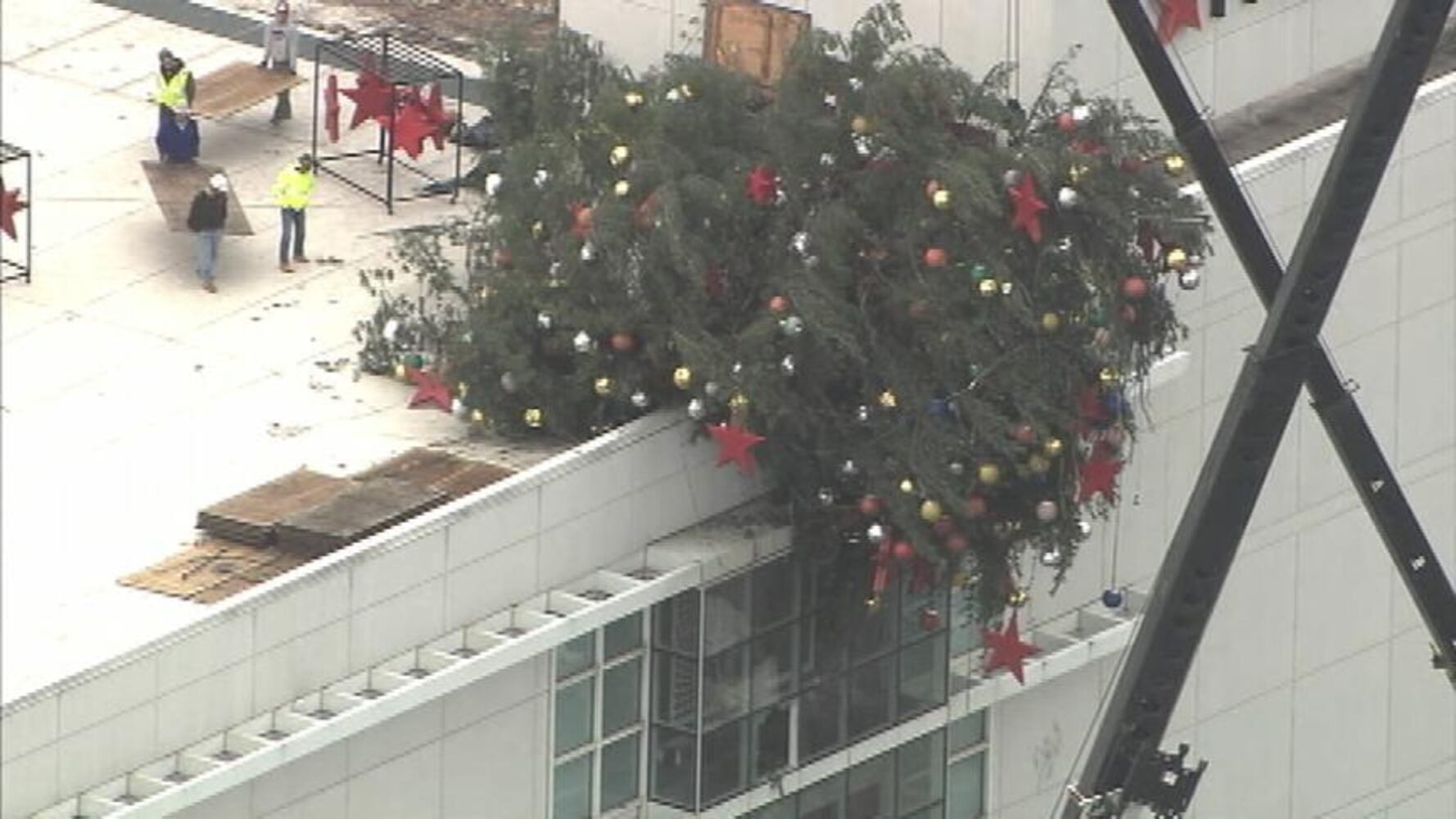 Crane buckles, leaving Christmas tree hanging off roof