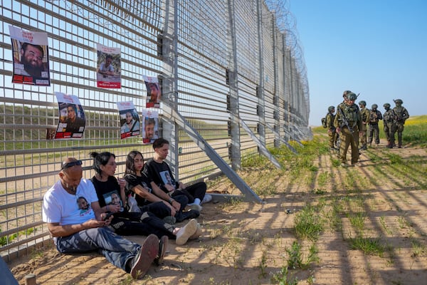 Relatives of hostage held by Hamas in the Gaza Strip, sit by the Israe-Gaza border fence, escorted by Israeli soldiers, calling for their release and expressing concerns that the resumption of fighting in Gaza puts their loved ones at risk, in southern Israel, Tuesday, March 18, 2025. (AP Photo/Ohad Zwigenberg)