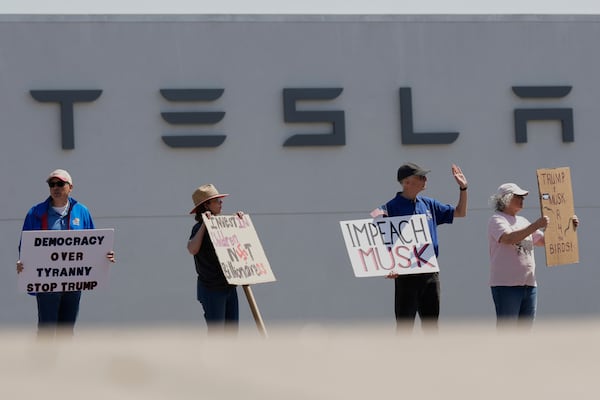 Demonstrators protest against Elon Musk and Department of Government Efficiency cuts outside a Tesla dealership, Saturday, April 12, 2025, in Kansas City, Mo. (AP Photo/Charlie Riedel)