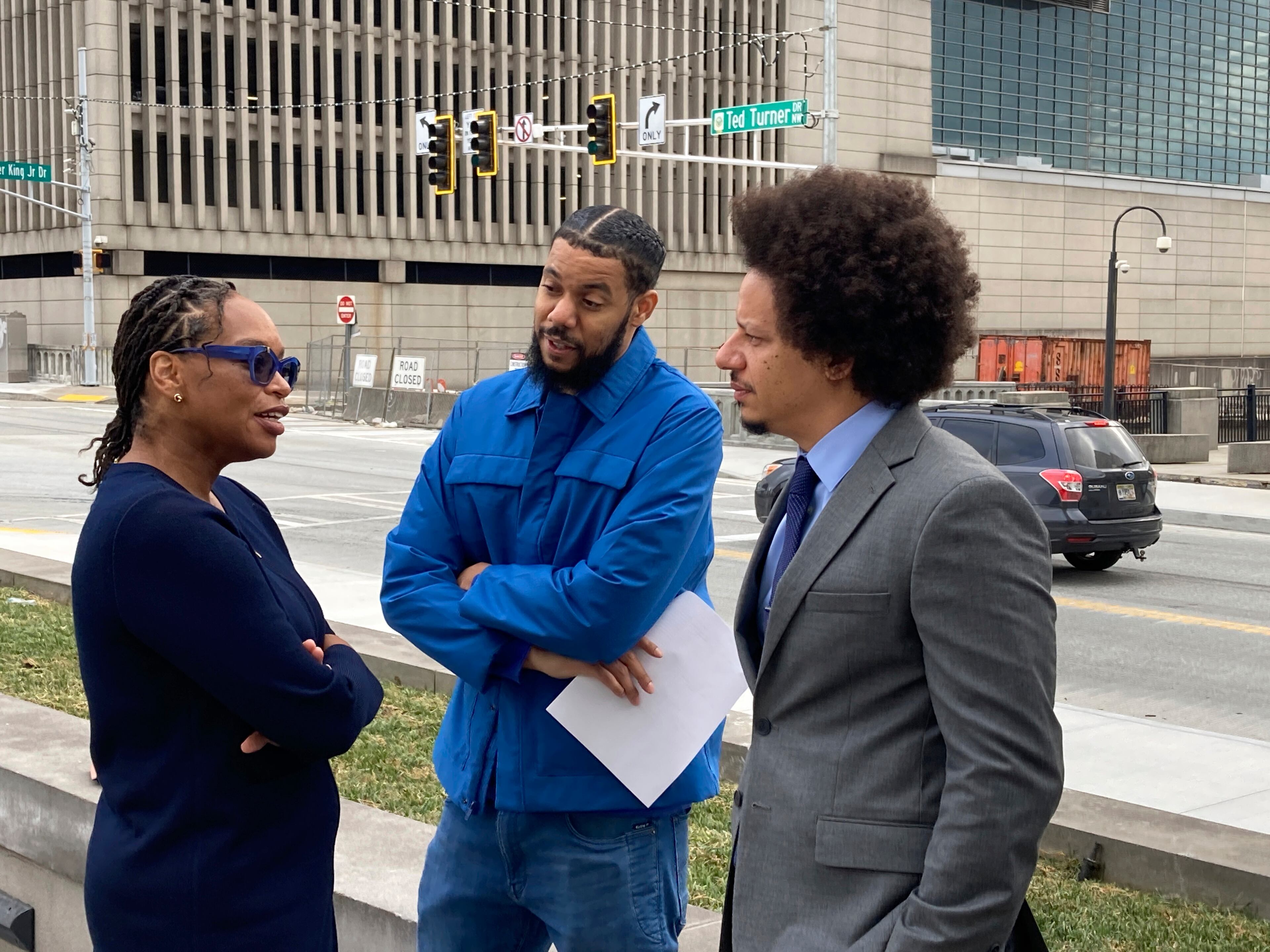 Comedians Clayton English, center, and Eric André, right, speak with their attorney in 2022.
