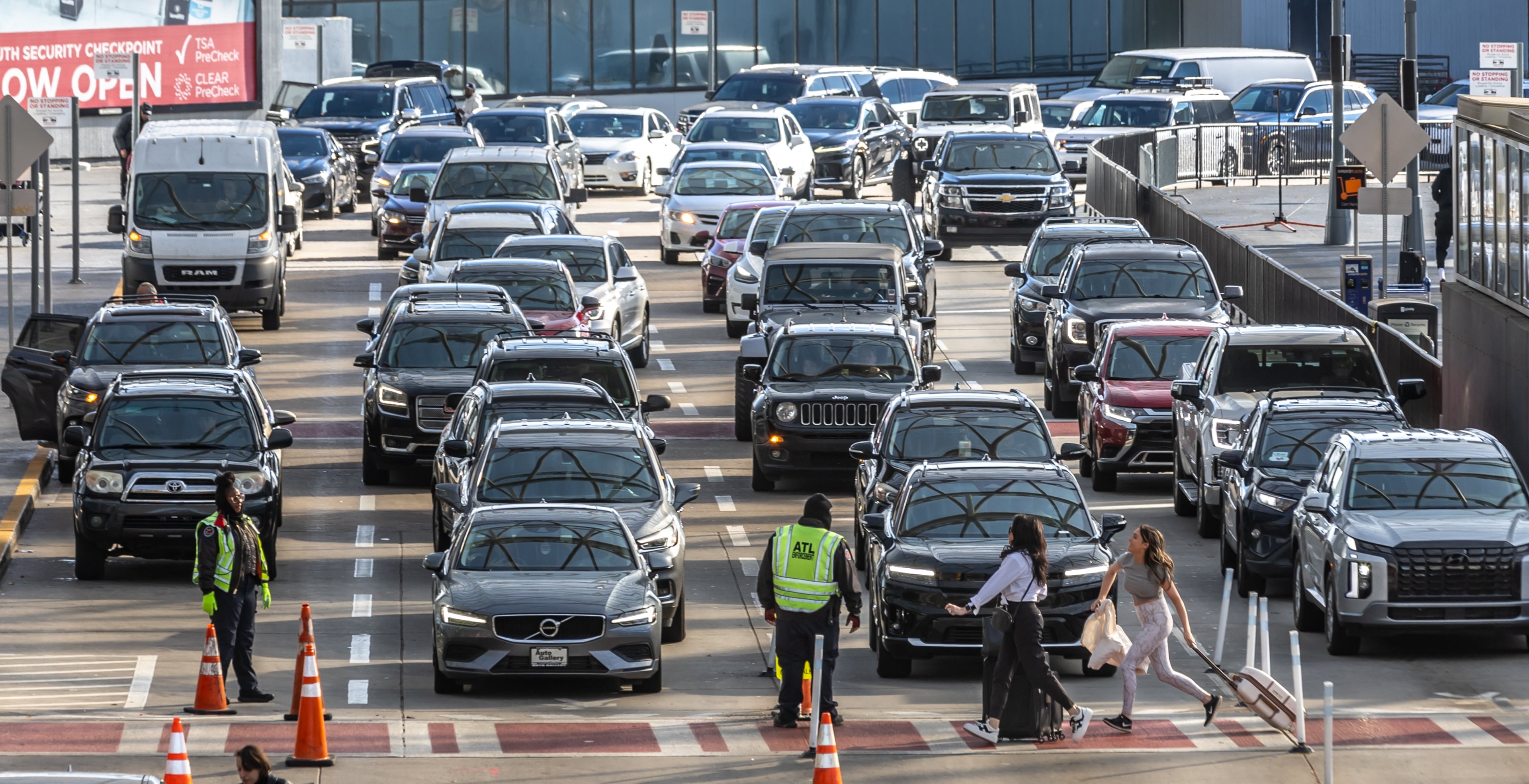 Travelers make their way past a sea of cars late last November at the airport. (John Spink / AJC)